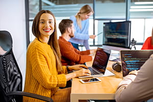 Team of a young woman as a programmer sitting in the office with people working on the background